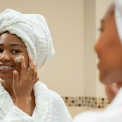 a woman with a towel on her head and a jar of cream on her face